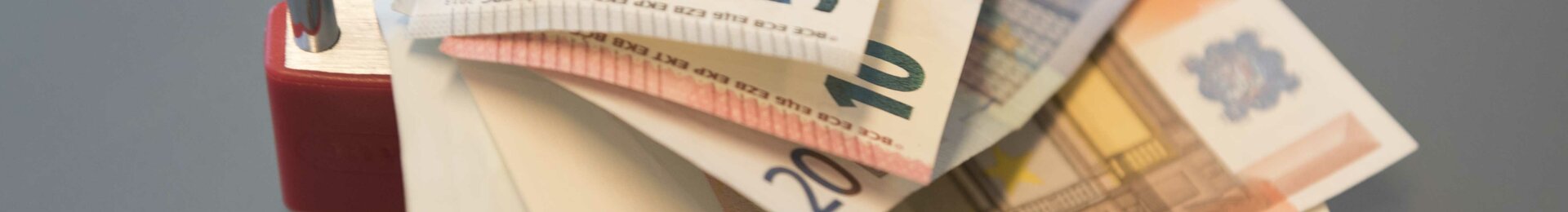 Euro-Scheine unter einem geöffneten Vorhängeschloss