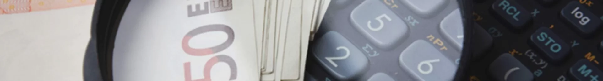 Lupe über Euro-Scheinen auf einem Taschenrechner